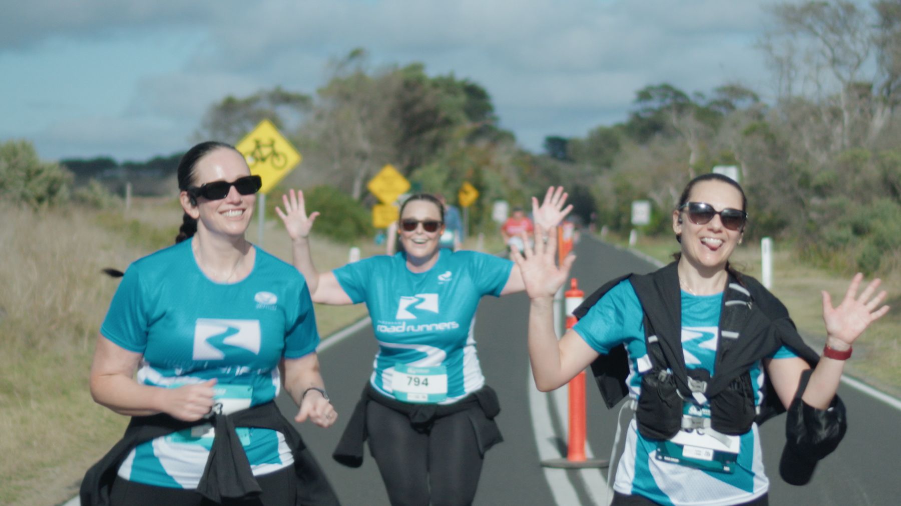 Group of runners waving on the coast road